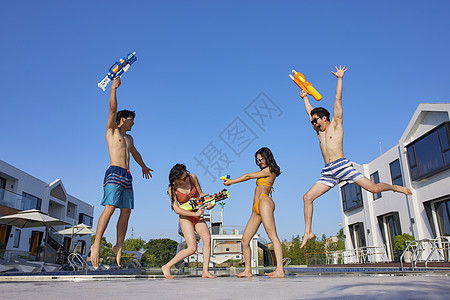 快乐的年轻人们在泳池边打水仗图片