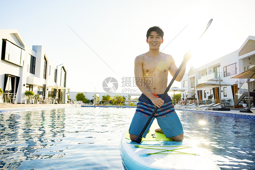 男青年夏日度假水中玩桨板图片