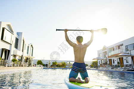 男青年夏日度假水中玩桨板背影图片