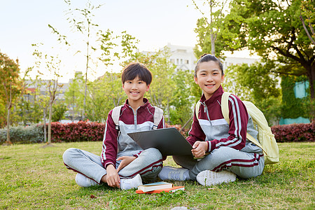 小学生坐在草坪上交流学习形象图片