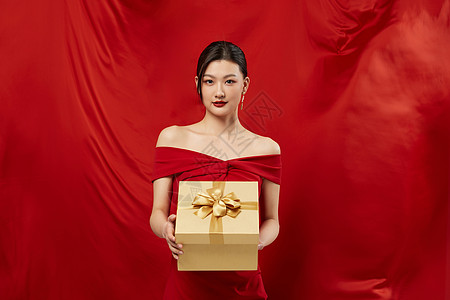红色背景手拿礼盒的性感女性图片