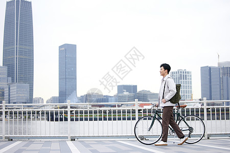 骑自行车青年年轻男性江边推着自行车行走背景