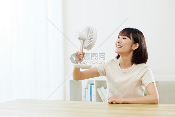 夏日女生在家用风扇解暑图片
