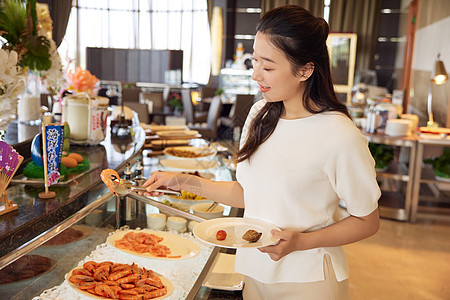 女性在自助餐厅挑选菜品图片