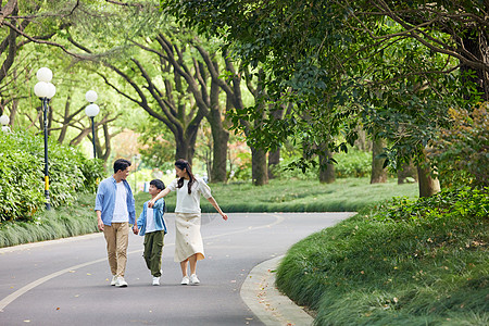 六一儿童节一家人在林荫道路散步背景