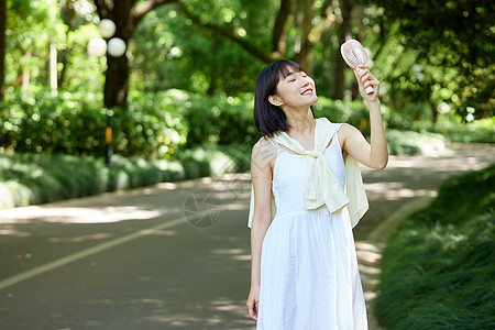 公园里小风扇吹风的少女高清图片