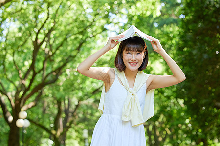 女生户外头顶书本图片