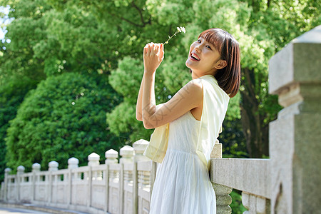 夏日少女手拿野花站在桥边图片