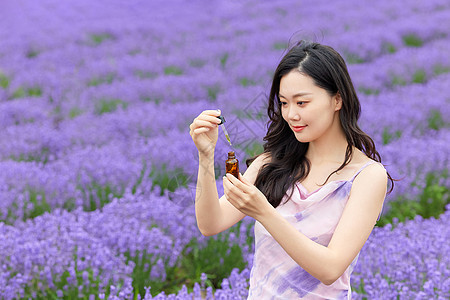 手拿精油站在薰衣草花海的女性图片