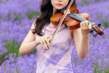 薰衣草花田里拉小提琴的女性特写图片