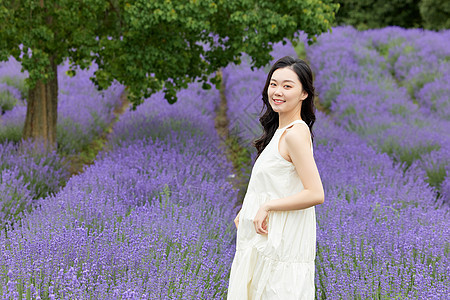 在薰衣草花田散步回头的女性图片