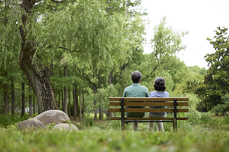 夫妻亲密老年夫妇坐在公园长椅背影背景