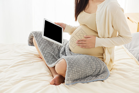 居家养胎的孕妇看pad特写图片