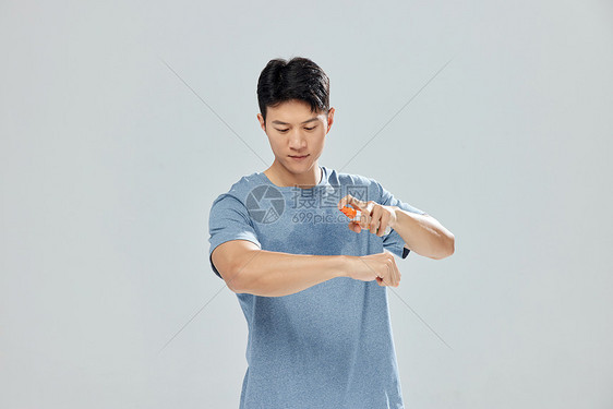 用驱蚊液喷手臂的男子图片