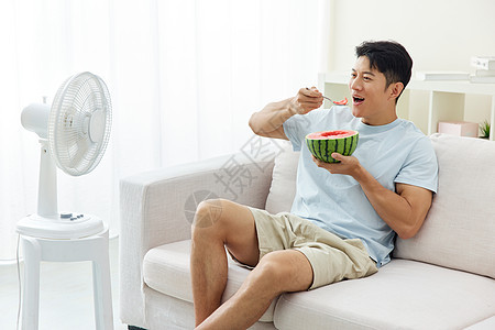 居家吃西瓜吹风扇的男人图片