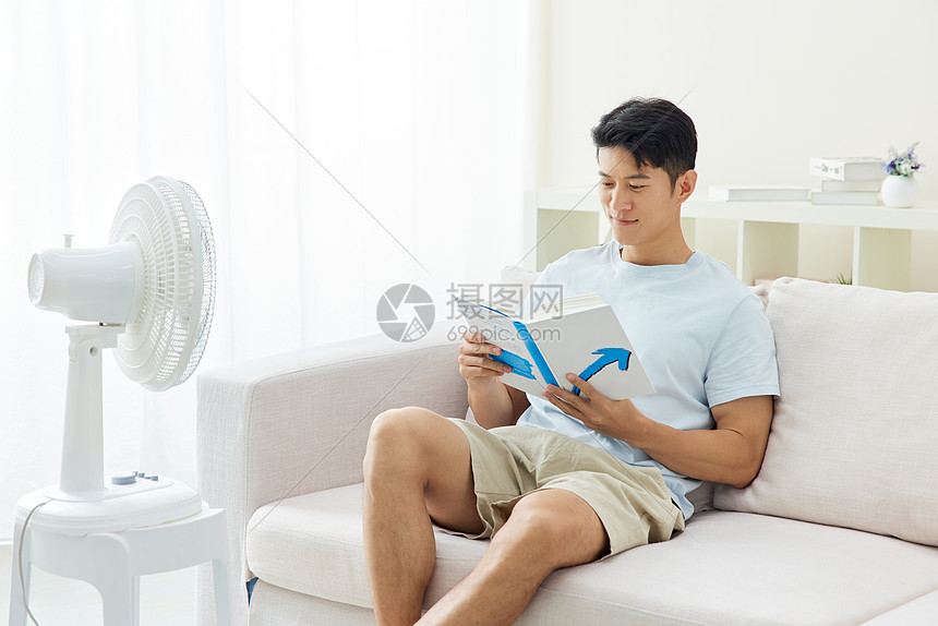 男人在沙发上吹着风扇阅读图片