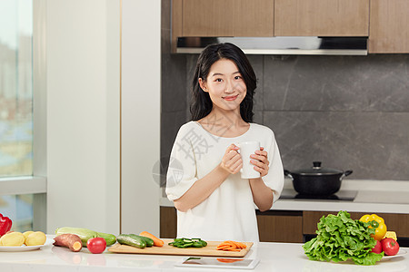 女性手捧饮品站在餐桌边形象图片