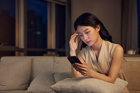 坐在沙发夜晚独自坐在客厅看手机的女人背景