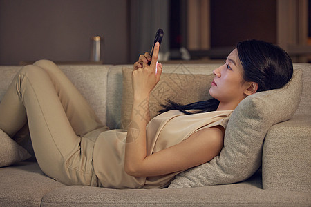 躺在沙发上玩手机的女性形象图片