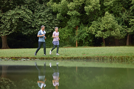 河边草坪上跑步的老夫妻图片