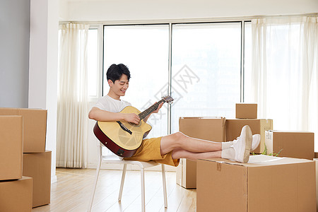 双脚架在纸箱上弹奏吉他的男人图片