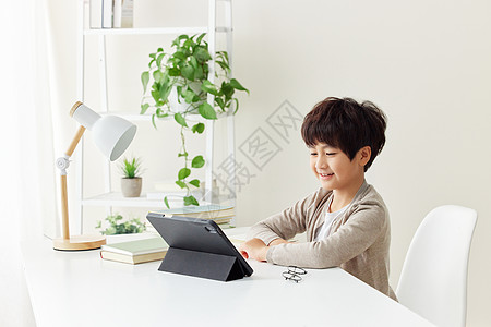 端坐在书桌前看平板电脑的小男孩图片