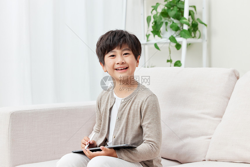 沙发上使用平板电脑的男孩形象图片