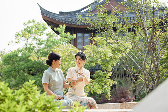 旗袍女性在中式庭院里品尝月饼图片