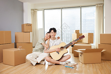 在新家地板上弹奏吉他的情侣形象图片