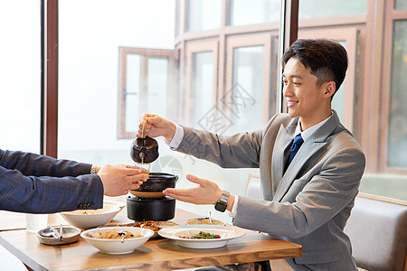 同伴们商务人士吃饭给同伴倒茶背景