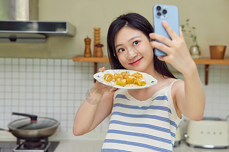 下厨的女生使用手机记录美食图片