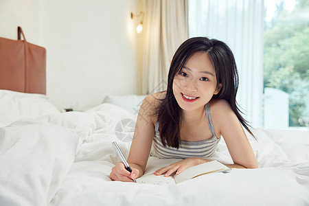 趴在床上写日记的可爱女生图片