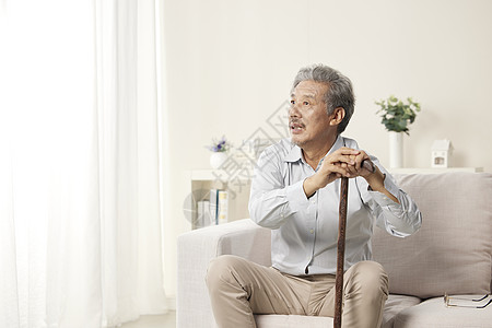 沙发上拄着拐杖的老年形象背景图片