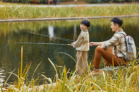 男孩站在河边和父亲一起钓鱼图片