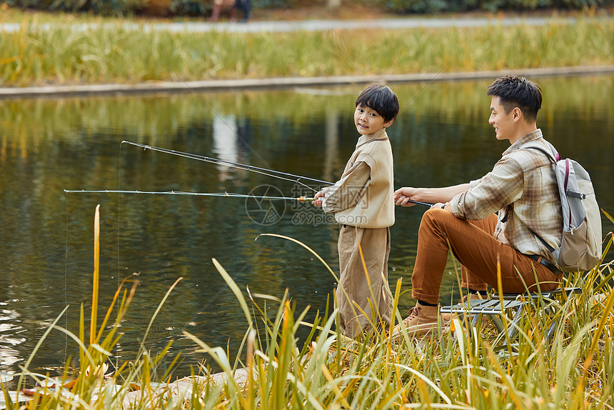 男孩站在河边和父亲一起钓鱼图片