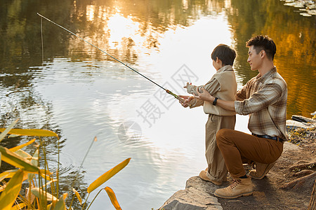 父亲教男孩在河边钓鱼高清图片