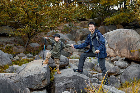 男孩和父亲手拉手站在石头上图片