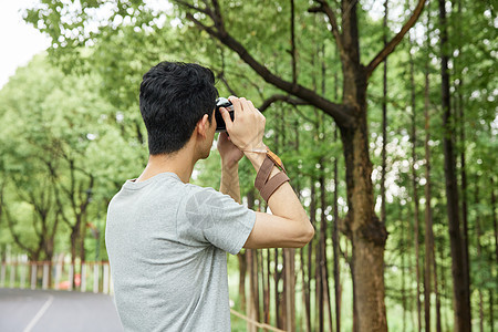 在公园手拿相机的年轻男性图片