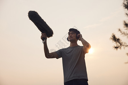 夕阳下的收音工作人员剪影图片