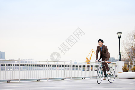 在江边骑行的商务男性形象图片