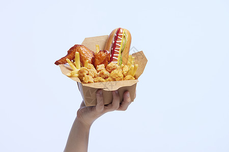 一只手举着装有高热量食物的快餐盒图片