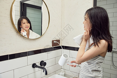 美女在浴室门口用吹风机吹头发图片素材
