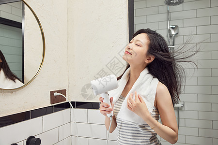 美女在浴室门口用吹风机吹头发图片