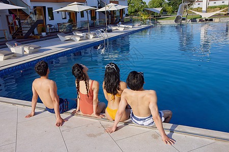 夏日泳池度假的青年男女背影图片