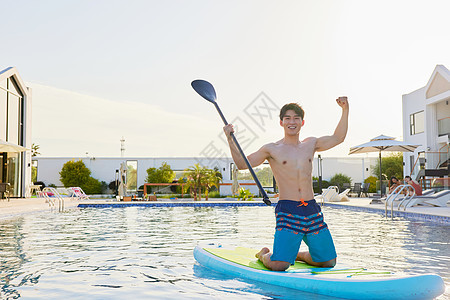 酒店泳池里高兴地划船的帅哥图片