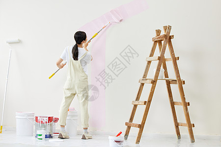 努力粉刷墙面的女性背影高清图片