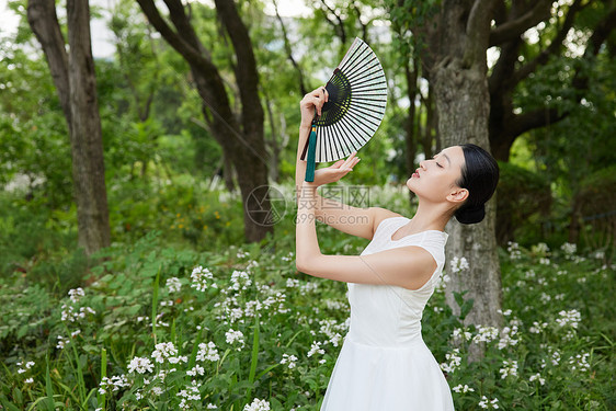 公园里舞扇子的白裙女子图片