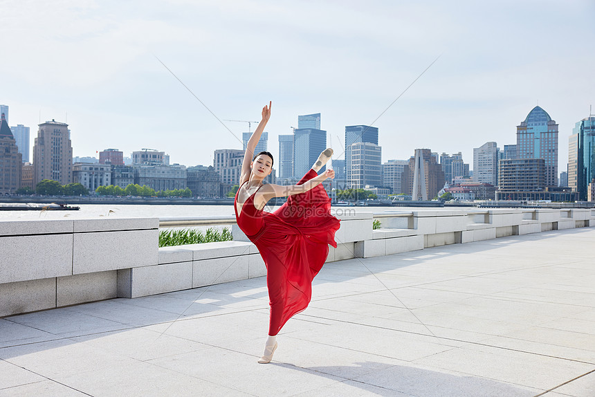 城市背景下翩翩起舞的红裙女子图片