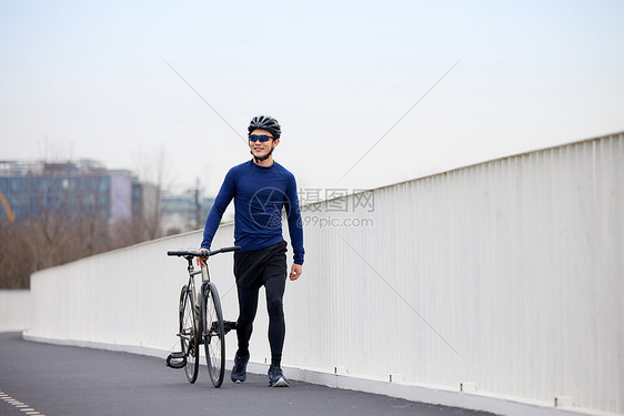 男子骑行过程中走路休息图片