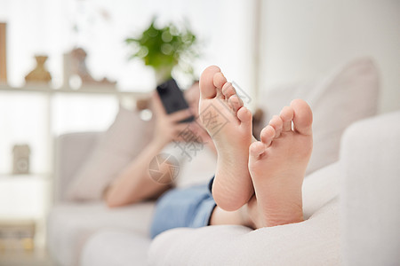 室内沙发上玩手机的女性脚底特写图片